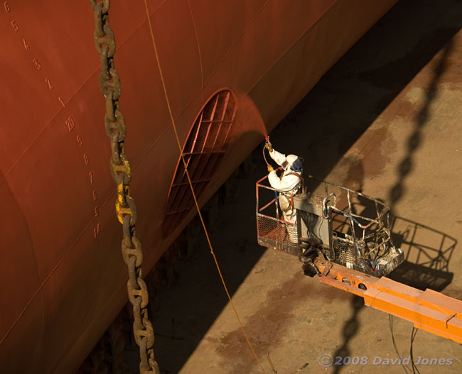 Spray-painting the hull of a container ship in dry dock