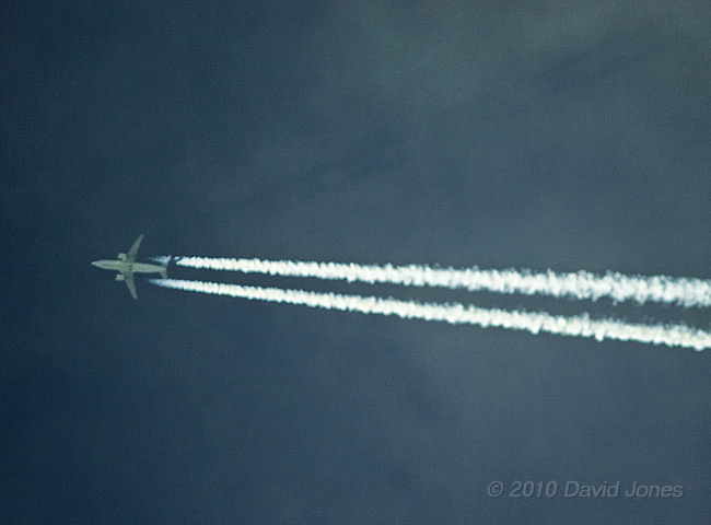 A jet produces a contrail and a shadow